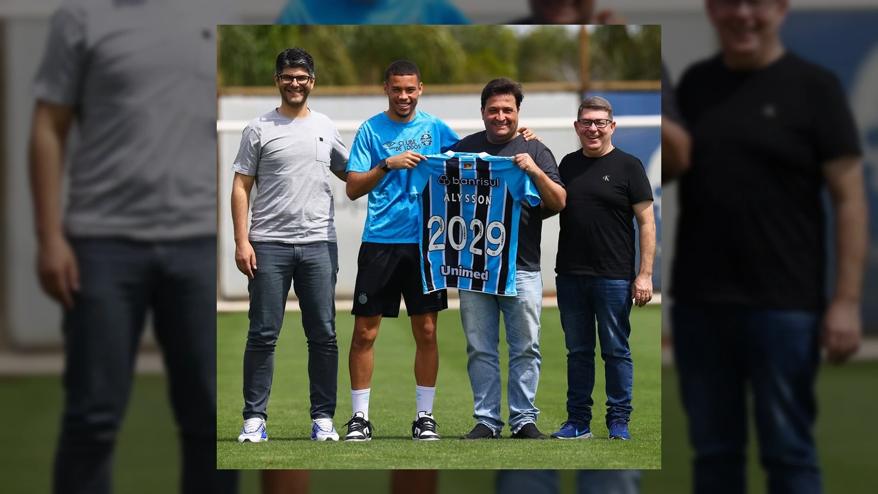 Foto de Alysson, atacante do Grêmio, ao lado de representantes do clube, segurando uma camisa com seu nome e o ano 2029, símbolo da renovação de contrato. Créditos ao Grêmio.